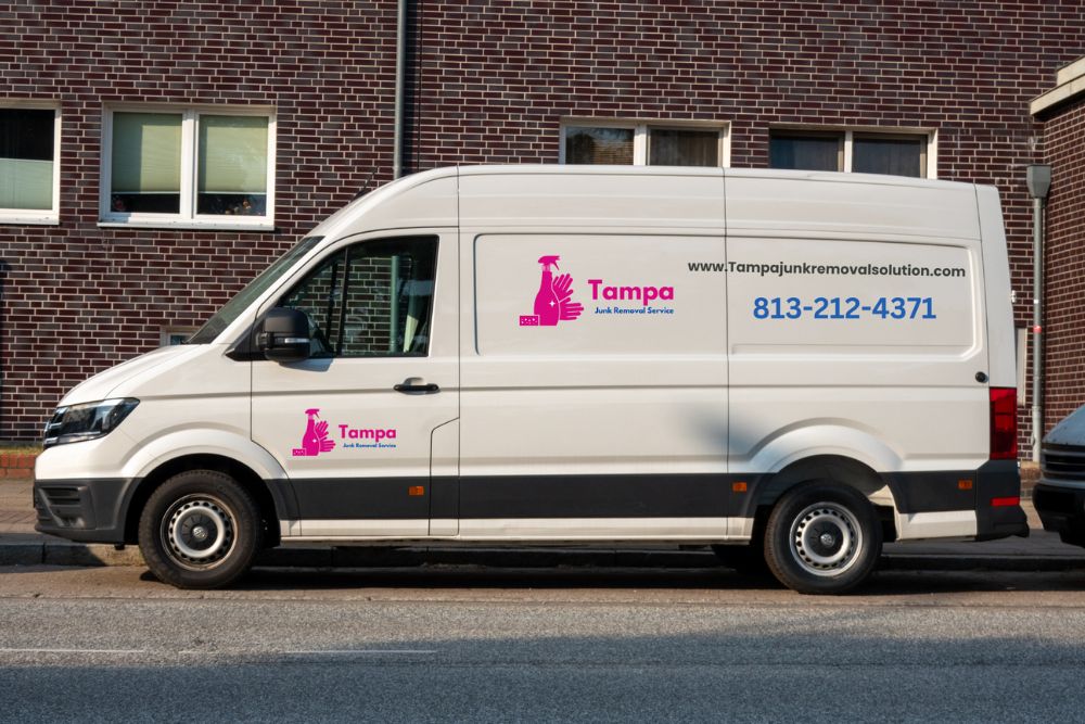 A pink-logoed van parked in front of a building, advertising a junk removal service in Tampa, Florida.