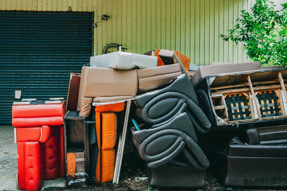 Outside a garage, a disorganized pile of furniture awaits removal, part of a clean-out service in Tampa, FL.