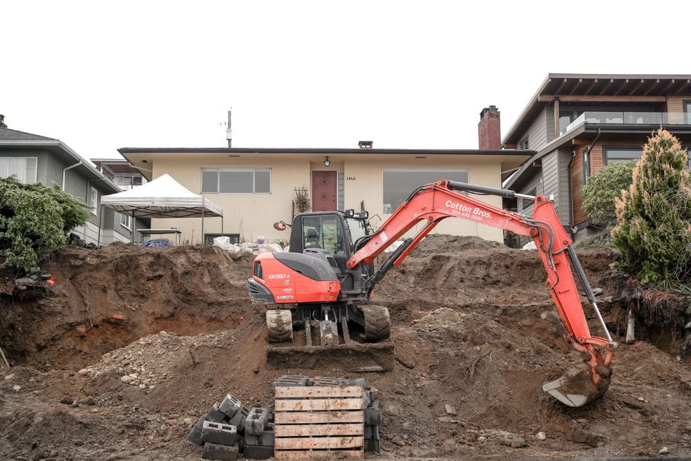 A red excavator is seen digging into the dirt, highlighting construction and renovation services in Tampa, FL.