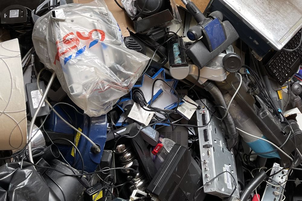 A room filled with a chaotic pile of electronics and other items, illustrating the necessity for e-waste junk removal services in Tampa, FL.